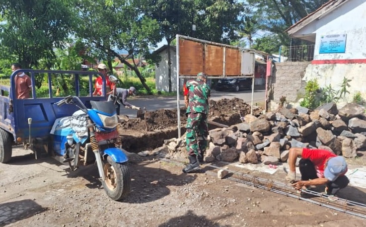 BANTU APDES, PELTU TATANG LAKSANAKAN PEMBUATAN PAGAR DEPAN DESA